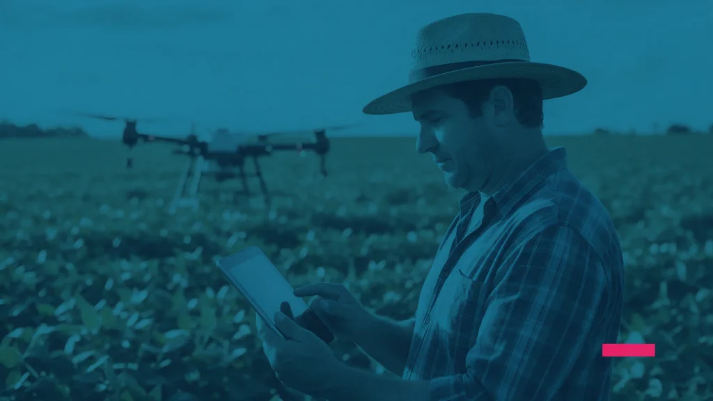 Produtor rural usando um tablet em uma plantação, com um drone ao fundo